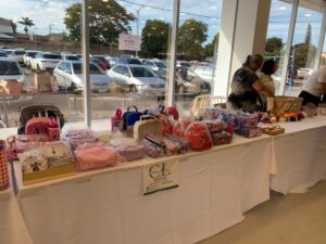 Dos artesanas organizan bolsos y manualidades en su stand durante la feria de artesanías por el Día de la Mujer Paraguaya.