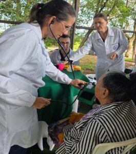 Estudiante controla la presión a una mujer mayor durante jornada de atención médica comunitaria en Saltos del Guairá.