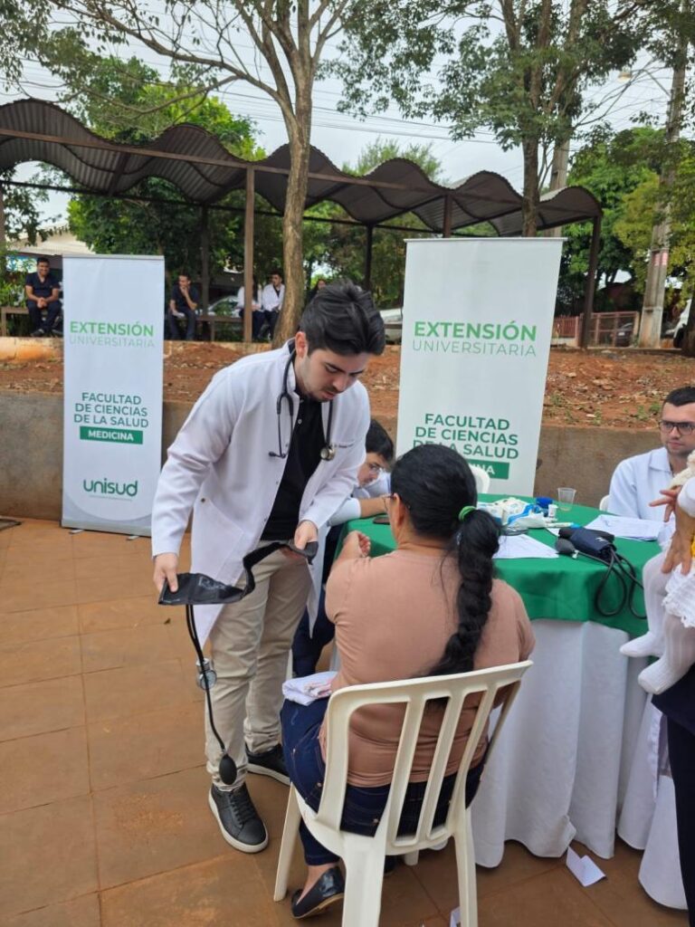 Estudiante de UNISUD toma la presión arterial durante una jornada de atención médica comunitaria en Saltos del Guairá.